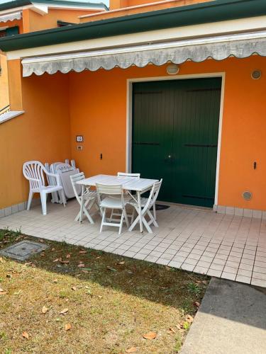 a patio with a table and chairs in front of a house at RESORT VILLAGE AQUA MARINA FAMILY - Daily Rooms Tidying - CocktailsBar- Pet Friendly - with Hypermarket - Delivery Restaurant-Pizzeria - Room Breakfast with supplement - Ultra Fast Wi-Fi - Play Area for children - Olympic Swimming Pool - Parking in Caorle