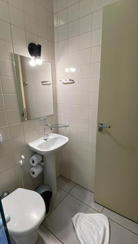a bathroom with a sink and a toilet and a mirror at Pousada Ilha Vitoria in Ubatuba