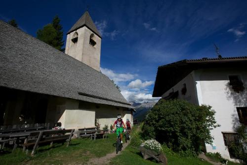 a person riding a bike in front of a church at Hotel Regglbergerhof in Nova Ponente