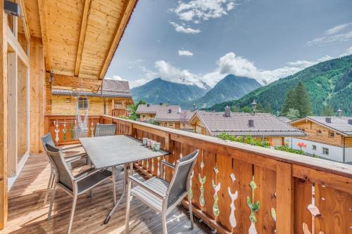 a balcony with a table and chairs and mountains at Chaletdorf am Sonnenhang in Neukirchen am Großvenediger
