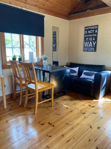 ein Wohnzimmer mit einem schwarzen Sofa und einem Tisch in der Unterkunft Lillstugan Lyckan in Kristdala