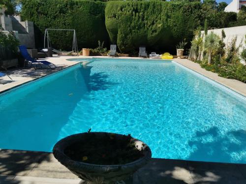 a blue swimming pool with a planter in a yard at Roulotte HOPE-Le jardin de Mia in Paradou