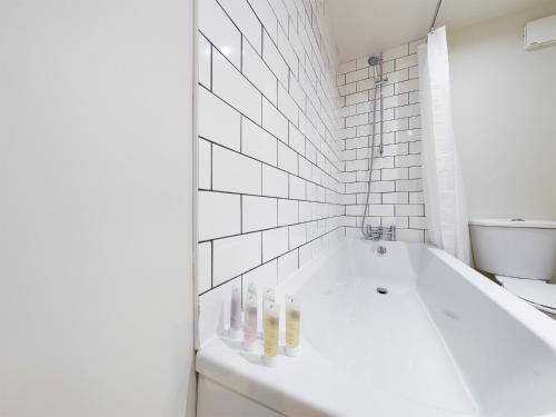 a white bath tub in a bathroom with white tiles at Redhill town centre apartment by Livingo in Redhill