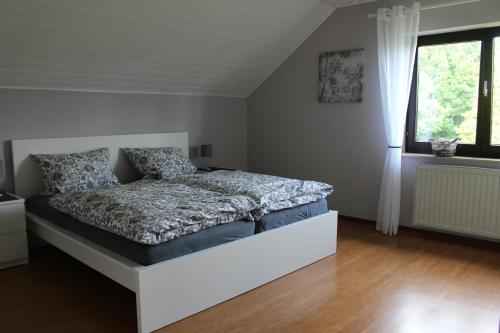 um quarto com uma cama num quarto com uma janela em Ferienwohnung Eifelbrise em Nideggen