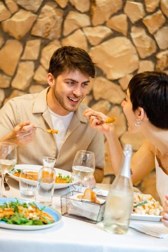 a man and woman sitting at a table eating food at New Bristol Sport Hotel in Cesenatico