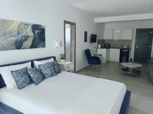 a bedroom with a white bed and a kitchen at All Blue Suites in Ambelas