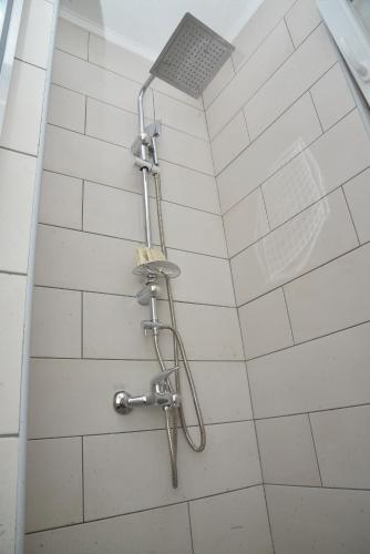 a shower in a bathroom with white tiles at Apartments Siesta in Ivanica