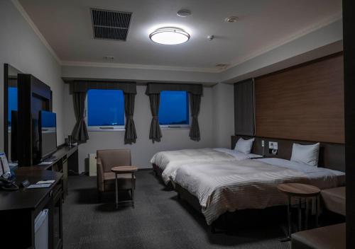 a hotel room with two beds and a television at Hotel New Palace in Shingu