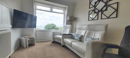 a living room with a white couch and a window at Three Beaches Holiday Apartments - close to Goodrington beach in Paignton in Paignton