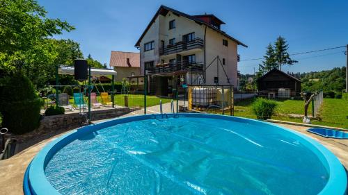 a large blue swimming pool in front of a house at Guest House Raukar in Crni Lug