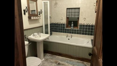 La salle de bains est pourvue d'une baignoire, d'un lavabo et de toilettes. dans l'établissement Traditional Stone lodge, Llandeilo, à Llandeilo