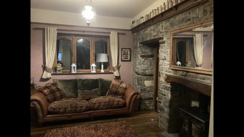 - un salon avec un canapé et une cheminée en pierre dans l'établissement Traditional Stone lodge, Llandeilo, à Llandeilo