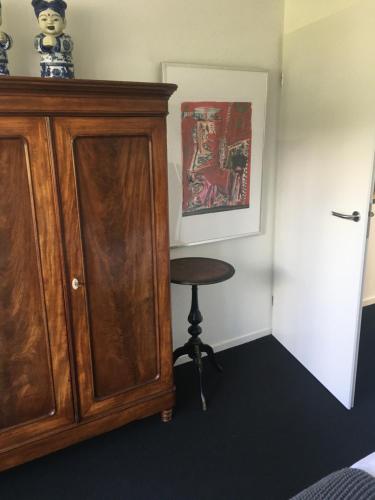 a bedroom with a wooden cabinet and a stool at Retour de Provence in Almelo