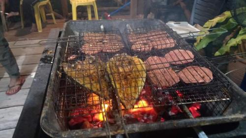 a grill with hot dogs and sausages on it at Bungalow Mat Hj Limah in Alor Setar