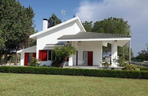 a white house with red doors and a yard at Villa CAPOROTONDO in Pisticci