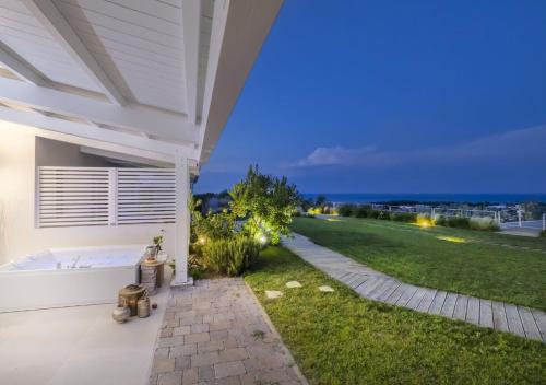 a white house with a bath tub and a grassy yard at Coppa Carrubo Residenza in Vieste