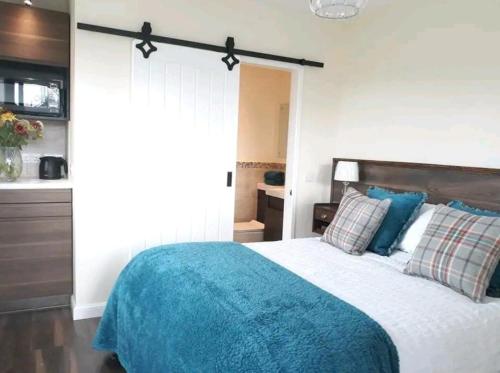 ein Schlafzimmer mit einem Bett mit einer blauen Decke in der Unterkunft The Wee Stay - Rural Guest Suite with outdoors Kitchen and covered Livingroom area in Crook of Devon