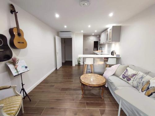 Sala de estar con sofá, mesa y guitarra en Bel appartement T2 dans résidence à Saint-Raphaël Valescure à 10 minutes de la mer, en Saint-Raphaël