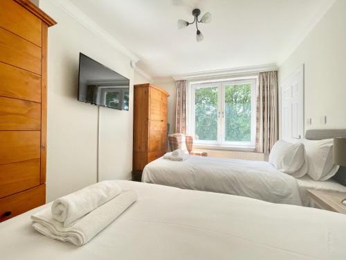 een slaapkamer met twee bedden en een tv aan de muur bij Clyde Villa in Glasgow