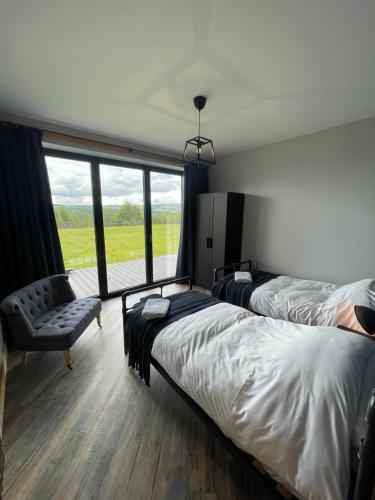 a bedroom with two beds and a chair and a window at Three-winds-guesthouse in South Crosland