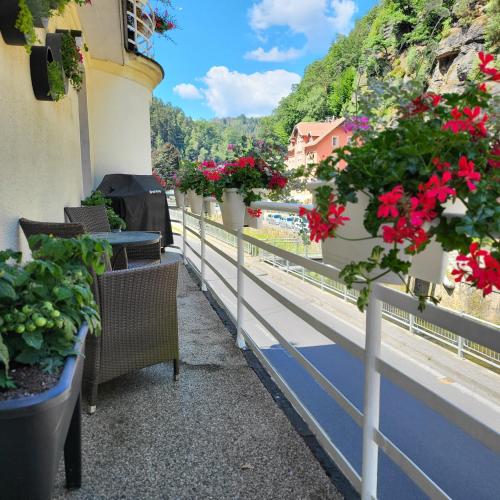 a balcony with flowers and tables and chairs at Apartment Villa Hřensko 132 in Hřensko