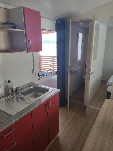 a kitchen with red cabinets and a sink and a bathroom at K9 Mobile Home Camp Imperial Vodice in Vodice