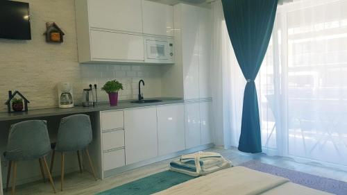 uma cozinha com armários brancos, um lavatório e uma janela em Garsoniera Camy em Saturn
