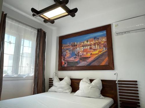 1 dormitorio con un cuadro sobre una cama con almohadas blancas en 3 Raum Fewo Griechenland, 400 m zum Strand, zwischen Thessaloniki und Kavala, en Ofrinion