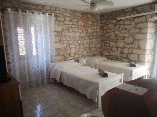 a bedroom with two beds and a stone wall at Apartment Julia in Nedeščina