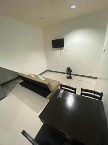 a room with a table and a couch and a television at Ma Lourdes' Inn in Palompon