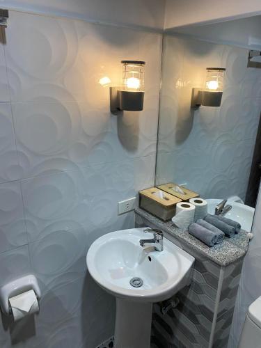 a white bathroom with a sink and a mirror at Ma Lourdes' Inn in Palompon