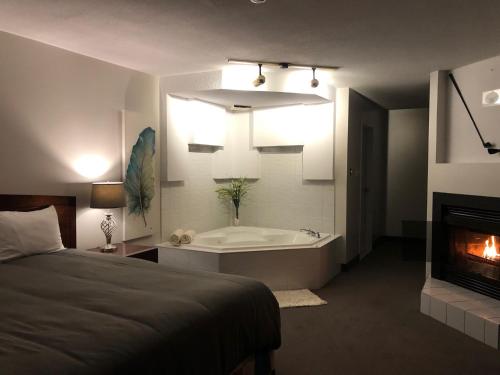 a bedroom with a bed and a tub and a fireplace at Auberge Matha in Saint-Jean-de-Matha