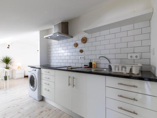 a white kitchen with a sink and a washing machine at GiG Capsule Hostel in Ericeira