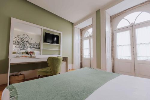 a bedroom with a bed and a desk and window at Trovador Guest House in Guimarães