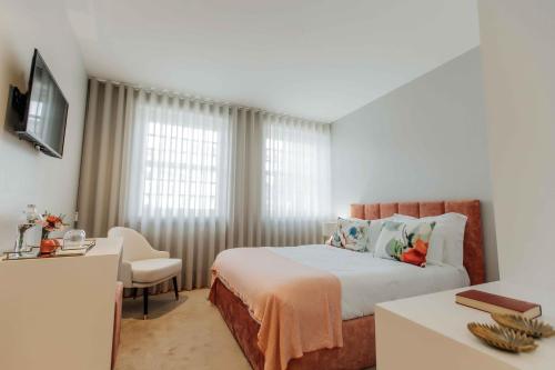 a bedroom with a bed and a desk and a window at Trovador Guest House in Guimarães
