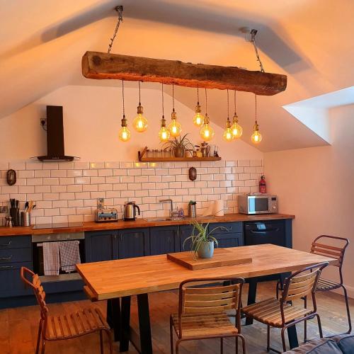 a kitchen with a wooden table and some lights at Bryansford Cottage Stables in Bryansford