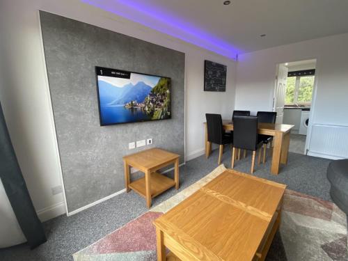 a living room with a table and a tv on the wall at Pure Apartments Fife - Dunfermline - Pitcorthie in Dunfermline