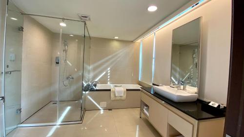 a bathroom with a glass shower and a sink at Golden Tulip Zhong Xin Hotel Taichung in Taichung