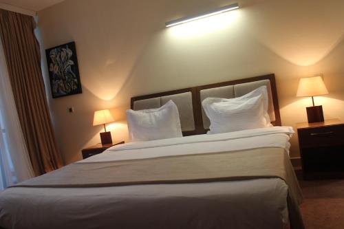 a bedroom with a large white bed with two lamps at Arena Hotel Kur in Mingachevir