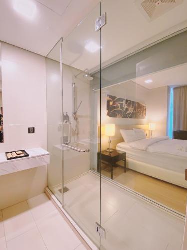 a glass shower in a bedroom with a bed at Straits Suite by C Homestay Malacca in Malacca