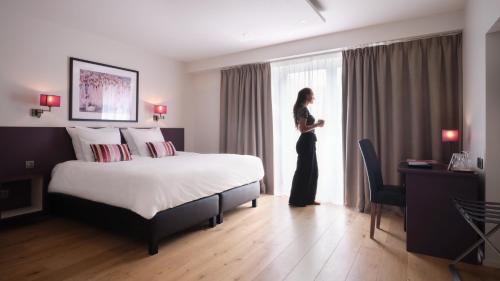 a woman standing in a hotel room looking out the window at Le 24 Hotel in Spa