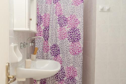baño con lavabo y cortina de ducha de color rosa y blanco en Villa Krina en Argasi