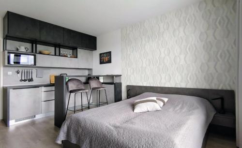 a bedroom with a bed and a kitchen with stools at Sunset Studio Apartment in Poprad