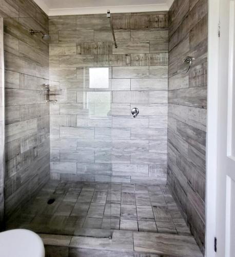 a bathroom with a shower with stone walls at Caribbean Estates 31 Montego Bay in Port Edward
