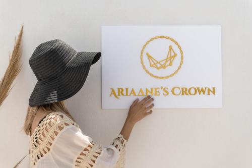 Una donna con un cappello che tiene un cartello sul muro di Ariadne's Crown Suites Astro Concept Luxury a Vívlos