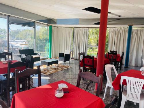 a restaurant with red tables and chairs and windows at Las Palmas del Daymán in Termas del Daymán