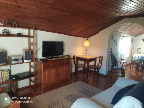 a living room with a tv and a table with chairs at ABRIGO DO CABECINHO - SERRA DA ESTRELA in Cortes do Meio