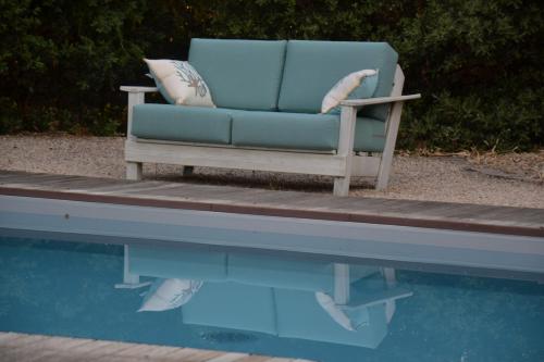 a blue chair sitting on a dock next to a swimming pool at Le gîte du petit branché in Mazan