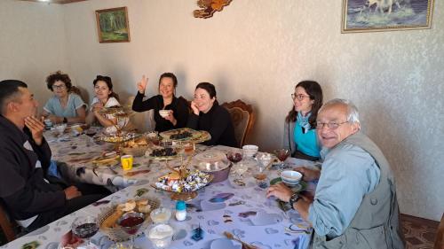 een groep mensen die rond een tafel zitten bij Kyzart Guesthouse in Bagysh