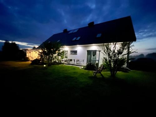 a white house with a bench in the yard at Dom w Trawach in Smołdziński Las